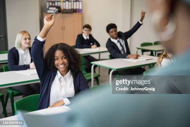smiling teenagers participating in classroom discussion - girl in uniform stock pictures, royalty-free photos & images