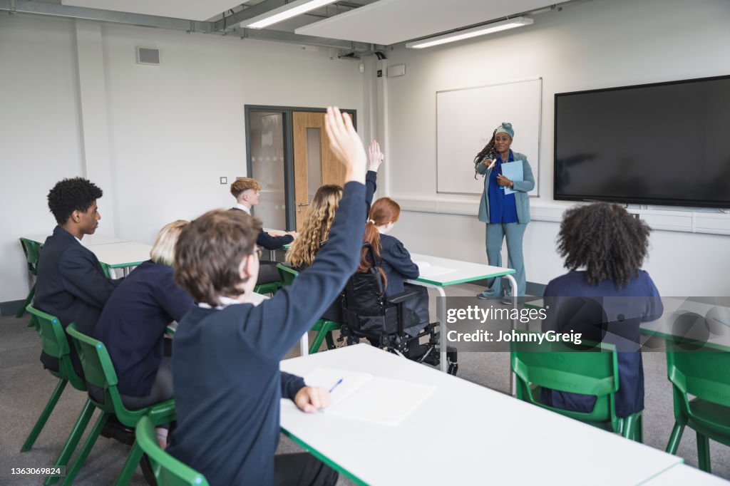 Teenage students interacting with teacher in classroom