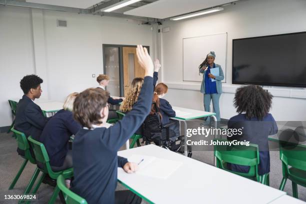 teenage students interacting with teacher in classroom - school uk stock pictures, royalty-free photos & images