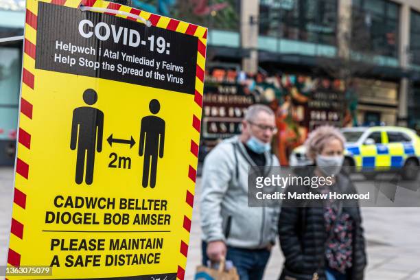 Close-up of a covid-19 warning sign in the city centre on January 3, 2022 in Cardiff, Wales. A revised version of alert level two measures was...