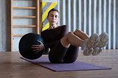 Woman doing russian twists with a medicine ball