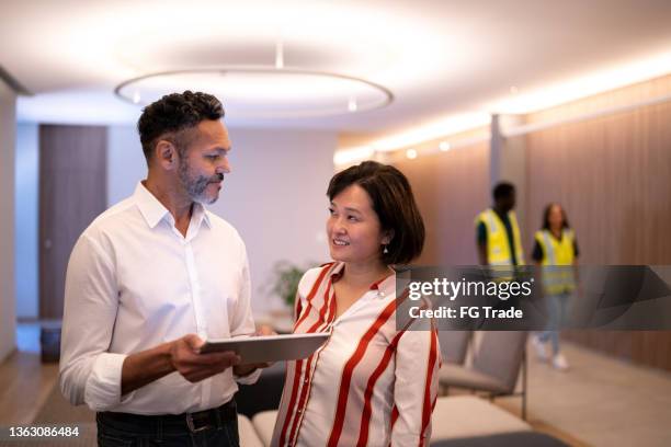 businesspeople talking and using digital tablet at the office's lobby - free trade hall stock pictures, royalty-free photos & images