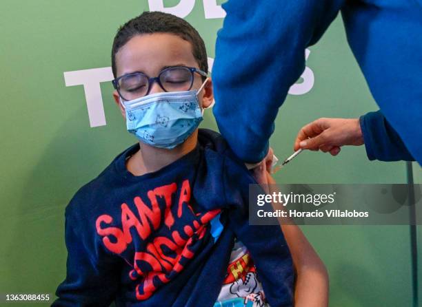 Ten-year-old child closes his eyes while receiving a children's dose of Pfizer-BioNTech at Palacio dos Congressos vaccination center on the first day...