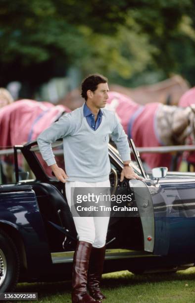 Prince Charles, the Prince of Wales playing polo at Cirencester, UK, 1st July 1986. Behind him is his Aston Martin DB6 Volante.