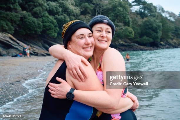 two female open water swimmers embracing - effort stock pictures, royalty-free photos & images