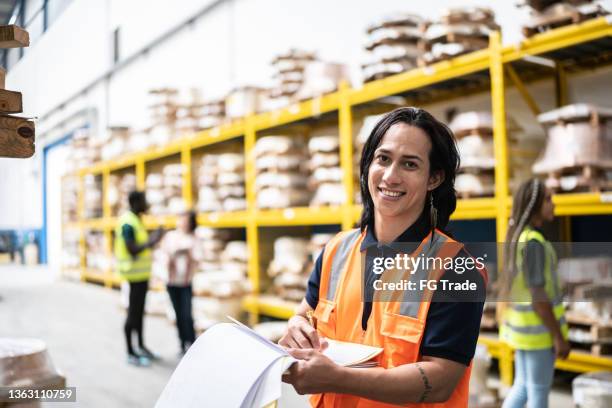 portrait of a non-binary employee taking inventory in a factory - non binary stereotypes stock pictures, royalty-free photos & images