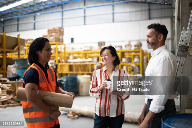 team having an informal meeting in a factory - including non-binary person - processing ideas stock pictures, royalty-free photos & images
