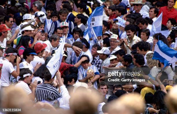 Argentina captain Diego Maradona cradles the trophy as he makes his way with other players through the fans after the FIFA 1986 World Cup final match...
