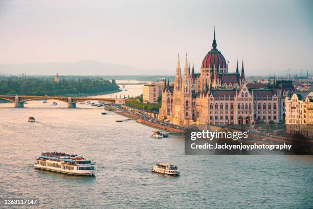 the hungarian parliament on the danube river at sunset in budapest, hungary - budapest skyline stock pictures, royalty-free photos & images