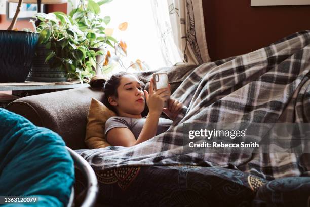 teenager on couch on phone - sadgirl stock-fotos und bilder