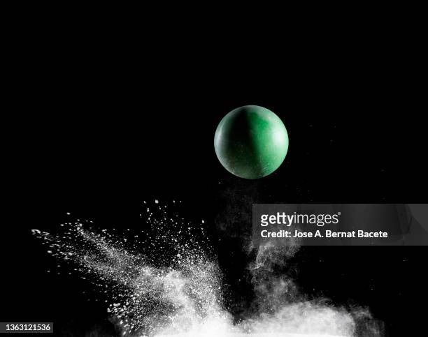 impact and rebound of a toy ball on a surface of land and powder on a black background - ballon rebond stock-fotos und bilder