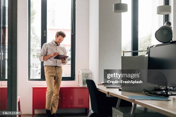 handsome young businessman using a digital tablet at work - splash news stock-fotos und bilder