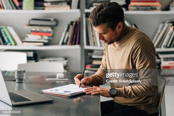 uomo d'affari laborioso seduto in ufficio analizzando i rapporti finanziari - teacher desk foto e immagini stock