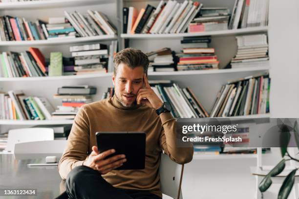 gutaussehender junger lehrer mit einem digitalen tablet in der bibliothek, vorbereitung auf einen vortrag - splash news stock-fotos und bilder