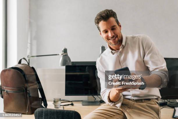 distrações no trabalho: jovem empresário bonito usando seu celular no escritório - camisa - fotografias e filmes do acervo