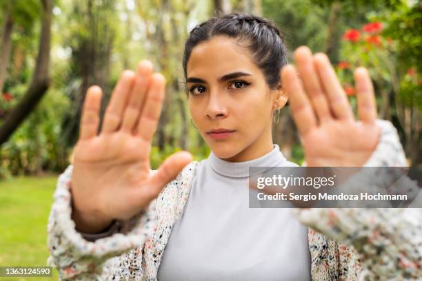 young latino woman looking at the camera and gesturing to stop - anti bullying symbols foto e immagini stock