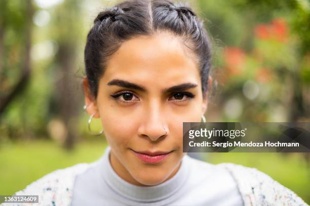 young latino woman raising an eyebrow and looking at the camera - raised eyebrows stockfoto's en -beelden