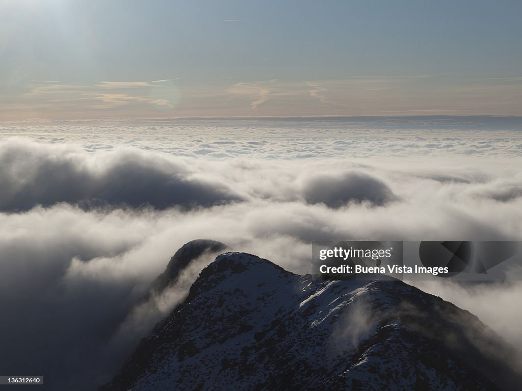 Lone climber on a peak in the clouds