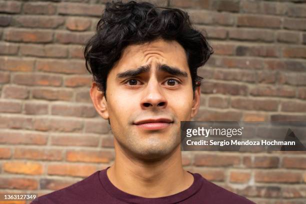 young latino man making a face looking uncertain, confused, perplexed, wtf - surprised expression stock-fotos und bilder