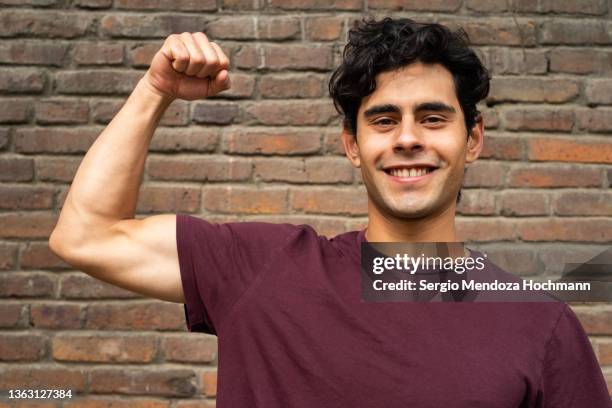 young latino man flexing his muscles and showing strength and determination - handsome mexican men - fotografias e filmes do acervo