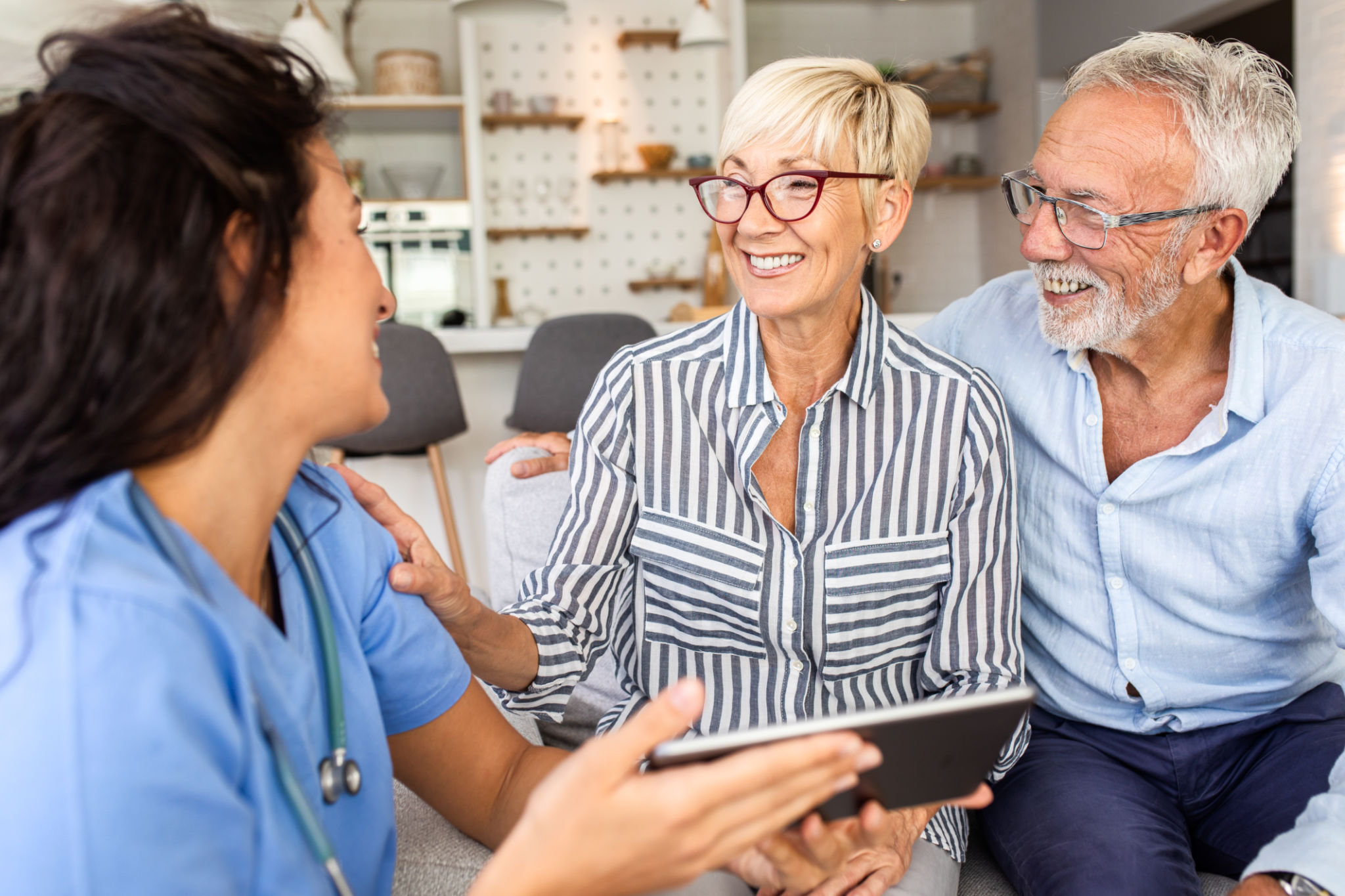 Female nurse talking to seniors patients while being in a home visit. Female nurse talking to seniors patients while being in a home visit.