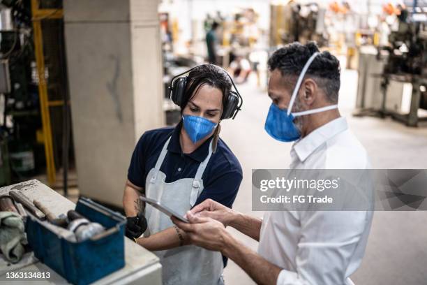 coworkers talking in a meeting at the factory/industry - using a face mask - including a non-binary person - employee engagement mask stock pictures, royalty-free photos & images