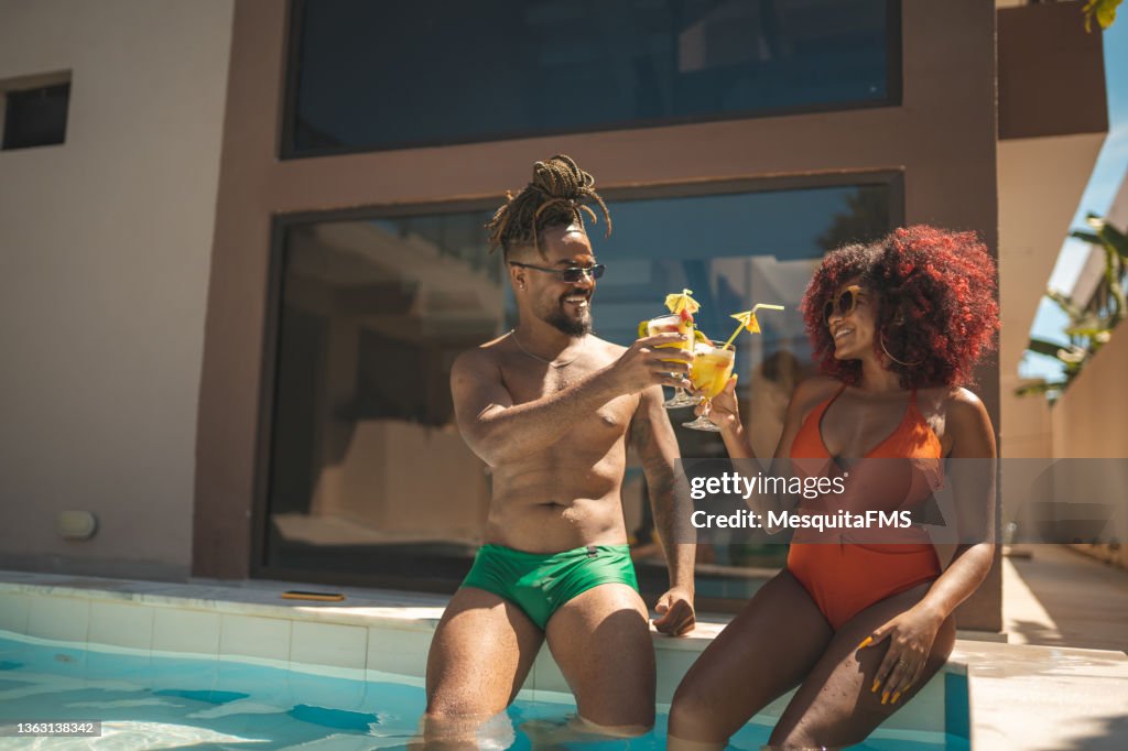 Afro couple having a tropical cocktail at the pool