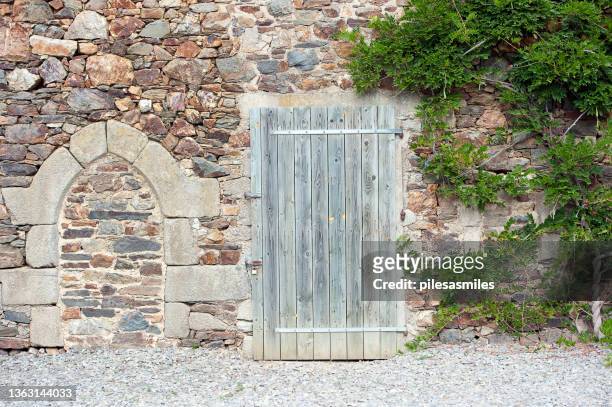 simple and plain wooden door and bricked arch in a stone wall in centre historique,  dinan, côtes-d'armor, france. - stone arch stock pictures, royalty-free photos & images
