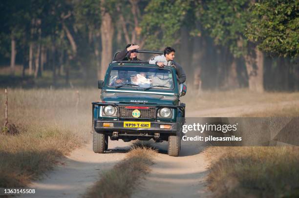 tourists and trackers share open-topped jeep off road 4x4 for animal viewing in kanha national park, madhya pradesh, india - madhya pradesh stock pictures, royalty-free photos & images