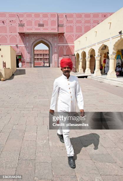 un homme du rajasthan vêtu de robes de vêtements traditionnels et d’un turban puggaree se promène dans le city palace, jaipur, rajasthan, inde - colors of india photos et images de collection