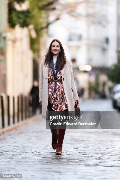 Alba Garavito Torre wears a blue vintage wool blazer jacket, a beige and burgundy floral print scarf over the blazer jacket, a turtleneck white...