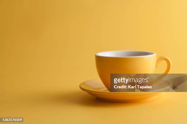 yellow coffee cup on a yellow background - cup stockfoto's en -beelden