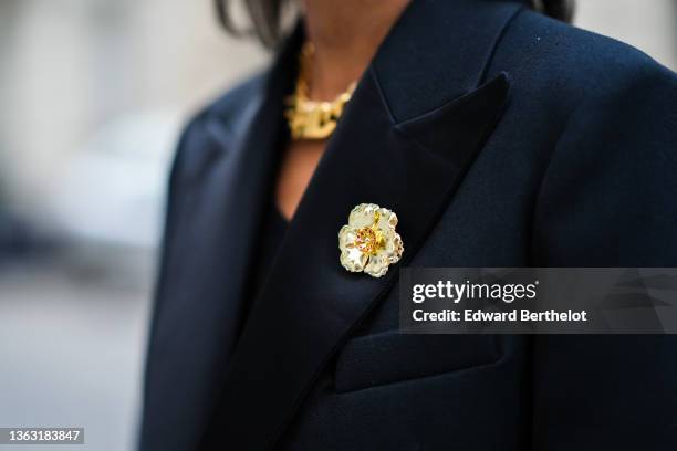 Emilie Joseph @in_fashionwetrust wears a long wool coat with tailored collar and golden floral brooch by Sandro Paris, a golden Necklace by Merbabe,...