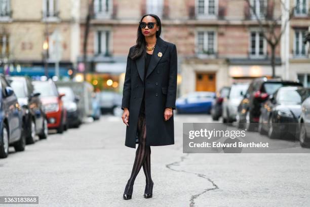 Emilie Joseph @in_fashionwetrust wears sunglasses, a long wool coat with tailored collar and golden floral brooch by Sandro Paris, Wolford suspender...