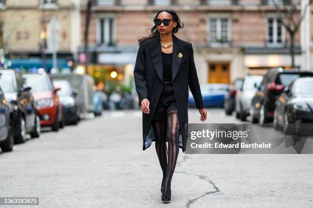 Emilie Joseph @in_fashionwetrust wears sunglasses, a long wool coat with tailored collar and golden floral brooch by Sandro Paris, Wolford suspender...