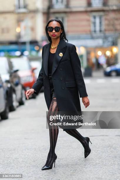 Emilie Joseph @in_fashionwetrust wears sunglasses, a long wool coat with tailored collar and golden floral brooch by Sandro Paris, Wolford suspender...