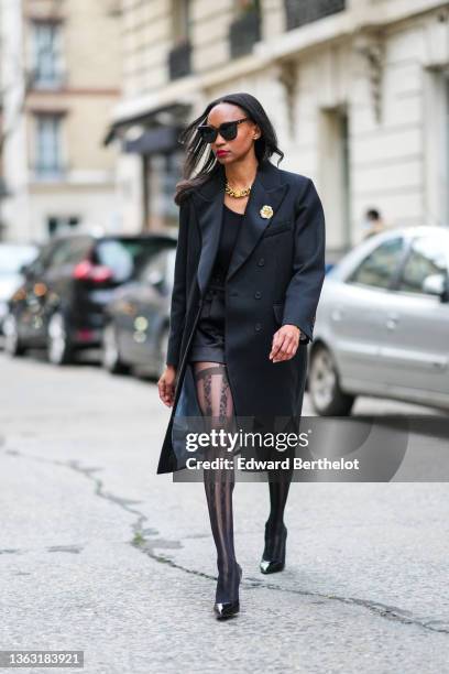 Emilie Joseph @in_fashionwetrust wears sunglasses, a long wool coat with tailored collar and golden floral brooch by Sandro Paris, Wolford suspender...