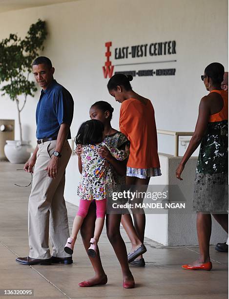 President Barack Obama watches while his daughter Sasha picks up his niece Savita Ng after a visit to the East-West Center at the University of...