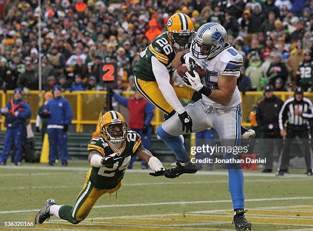 Tony Scheffler of the Detroit Lions catches a touchdown pass between Jarrett Bush and Charlie Peprah of the Green Bay Packers at Lambeau Field on...