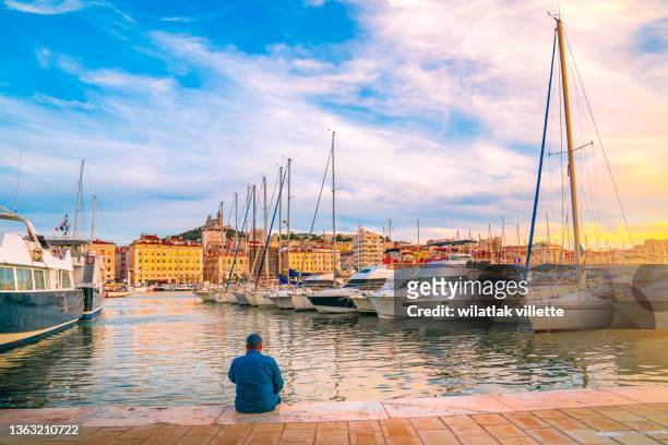 man sitting on the wooden pier at the river. - marseille stock-fotos und bilder