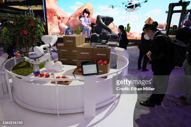 An attendee watches the Doosan Robotics M1013 and H2515 robots demonstrate their capabilities at CES 2022 at the Las Vegas Convention Center on...