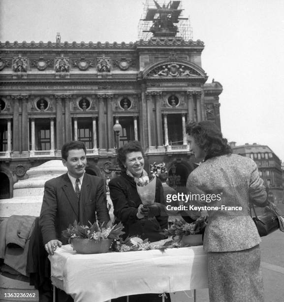 Un couple vend des bouquets de muguet sur la place de l'opéra pour la fête du travail, le 01 mai 1953.