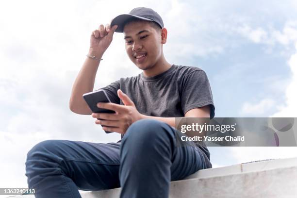 teenage boy using smartphone - teenage boy in cap posing stock pictures, royalty-free photos & images