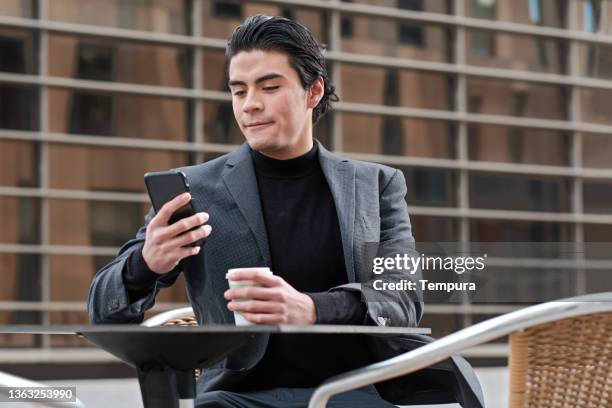 a young businessman is text-messaging on his smartphone. - spanish and portuguese people stock pictures, royalty-free photos & images