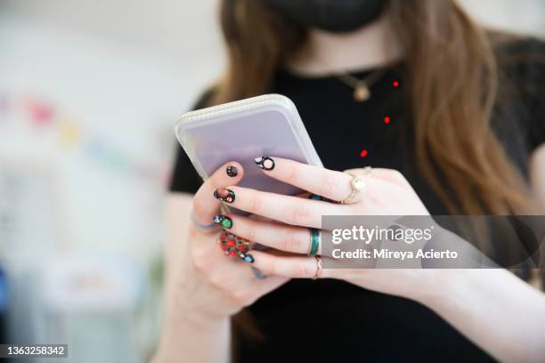 detail of a woman's hands using a cell phone, decorated with rings and painted nails of the solar system. - multi coloured nails stock pictures, royalty-free photos & images