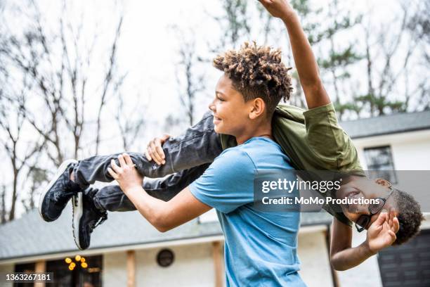 teen boys roughhousing in front of residential home - mixed wrestling imagens e fotografias de stock