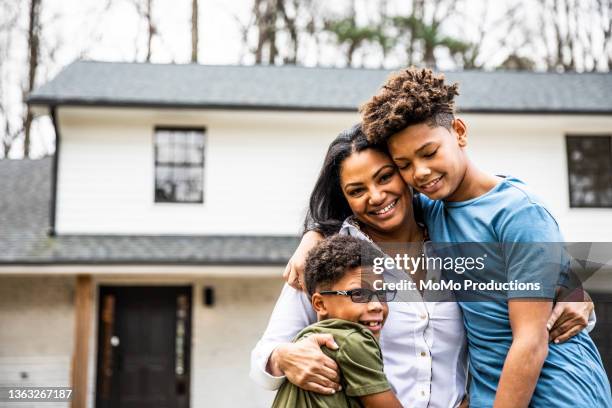 portrait of mother and sons in front of residential home - madre soltera fotografías e imágenes de stock