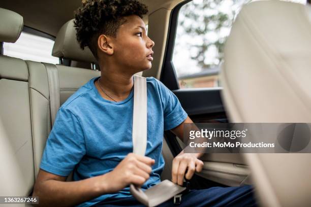 teen boy looking out window in the back of car - safe kids day arrivals stock pictures, royalty-free photos & images