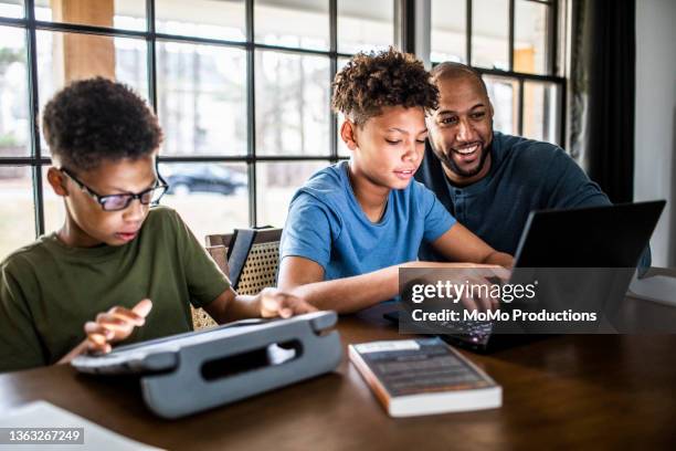 father helping sons with homework in residential kitchen - parent student stock pictures, royalty-free photos & images