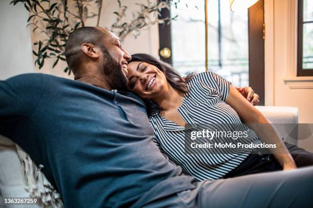 married couple embracing on sofa - man middelbare leeftijd woonkamer stockfoto's en -beelden